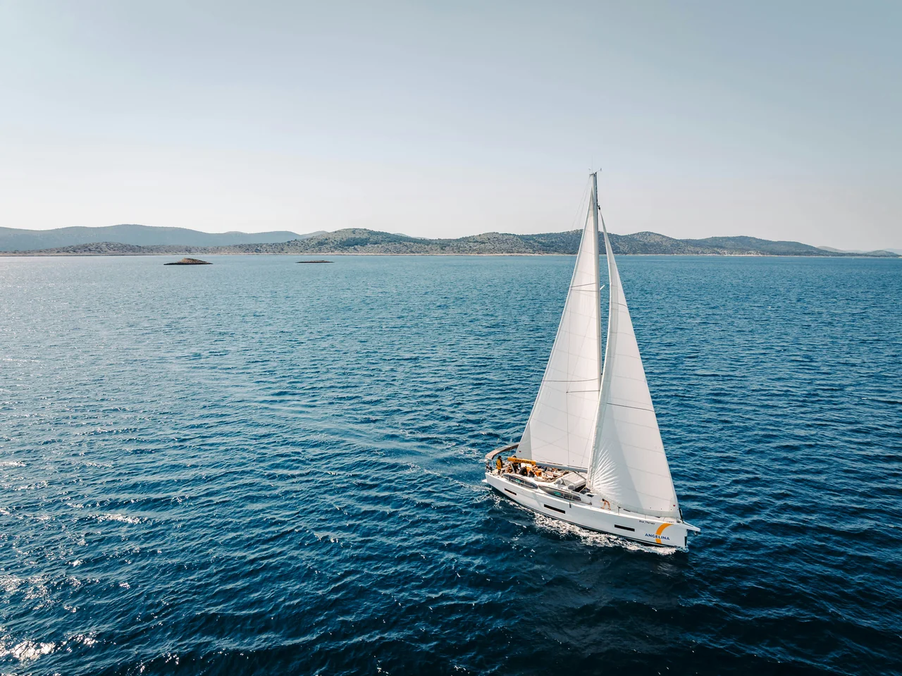 Una barca a vela bianca sul mare blu tra le isole Kornati